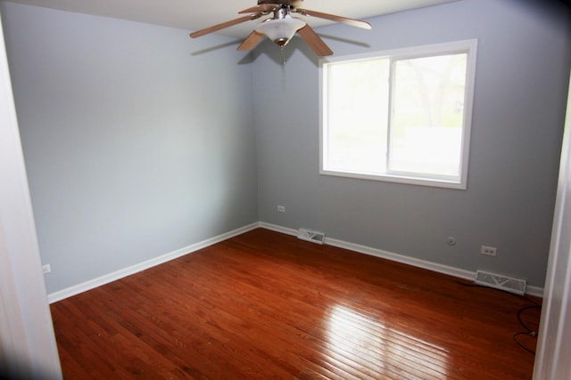 spare room with a ceiling fan, visible vents, and dark wood-style floors