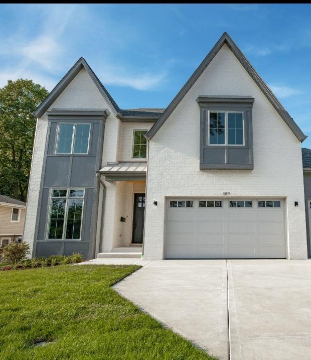 view of front of house featuring a standing seam roof, metal roof, driveway, a front yard, and an attached garage