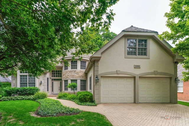 590 Academy Woods Dr, Lake Forest, IL 60045 - tudor home featuring stucco siding, stone siding, decorative driveway, and an attached garage
