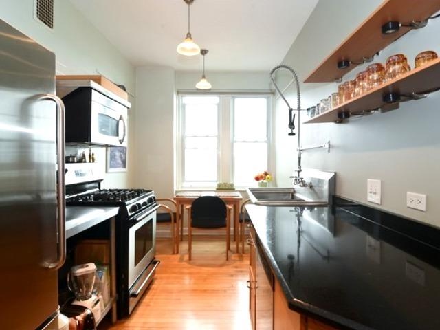 kitchen with appliances with stainless steel finishes, light wood-type flooring, a sink, and decorative light fixtures