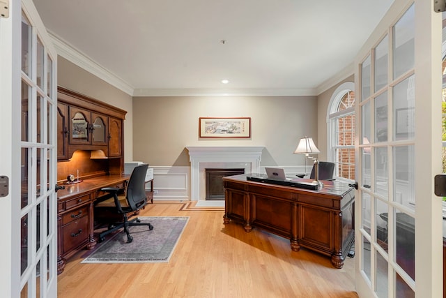 office with french doors, a fireplace, crown molding, light wood finished floors, and wainscoting