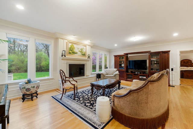 living room featuring a glass covered fireplace, light wood-type flooring, crown molding, and recessed lighting