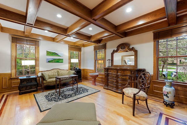 living area with wainscoting, beamed ceiling, plenty of natural light, wood finished floors, and coffered ceiling