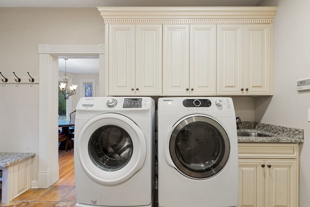 clothes washing area featuring cabinet space, washer and dryer, a chandelier, and light tile patterned floors
