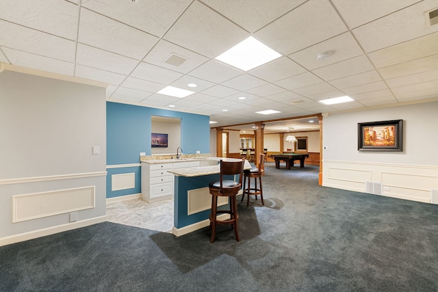kitchen featuring light carpet, a breakfast bar area, billiards, a paneled ceiling, and a sink