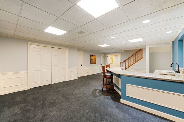 bar area featuring a sink, dark carpet, stairway, and wainscoting
