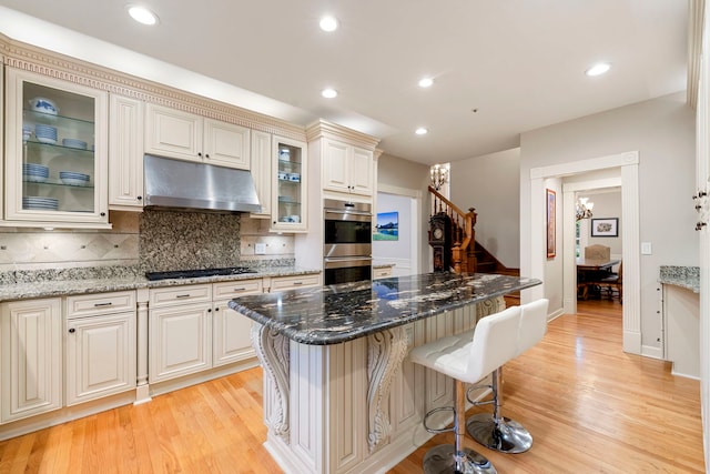 kitchen featuring under cabinet range hood, double oven, gas cooktop, light wood-style flooring, and recessed lighting