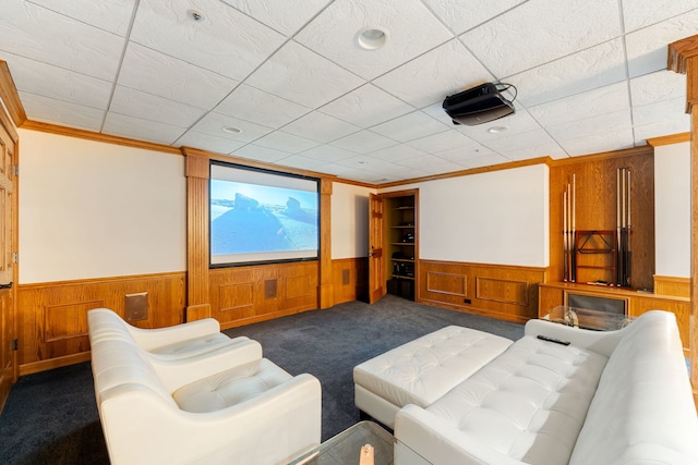 home theater with wainscoting, dark carpet, wooden walls, and ornamental molding