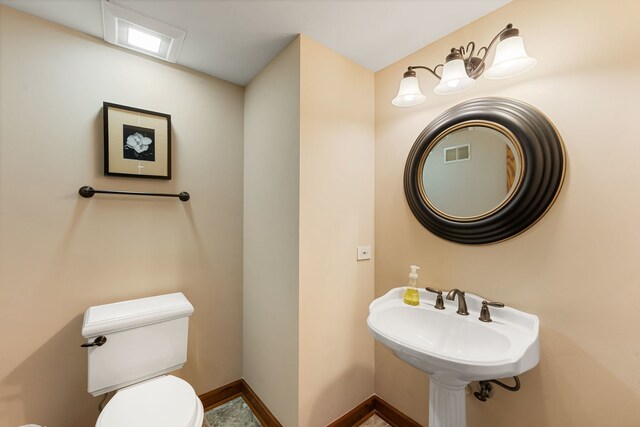 half bathroom with toilet, baseboards, and a sink