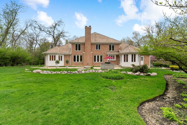 back of property with a chimney, a patio, a yard, and brick siding