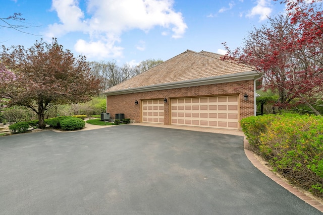 view of property exterior featuring brick siding, central AC unit, and driveway