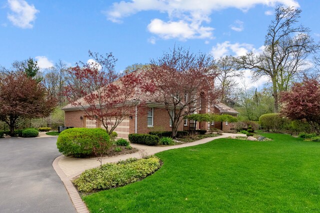 view of side of home featuring a lawn, driveway, brick siding, and a garage