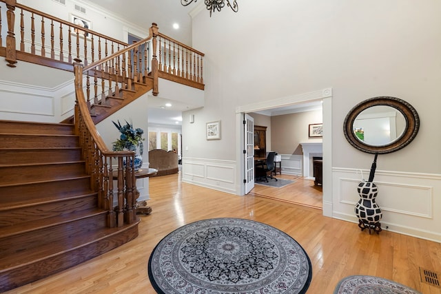 entrance foyer featuring wood finished floors, stairs, a decorative wall, a wainscoted wall, and a high ceiling