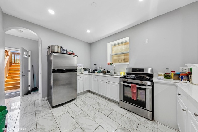 kitchen with appliances with stainless steel finishes, a sink, light countertops, marble finish floor, and recessed lighting