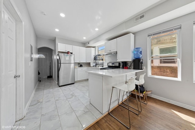 kitchen featuring appliances with stainless steel finishes, a peninsula, baseboards, white cabinetry, and visible vents