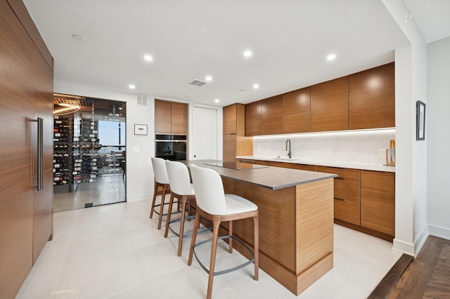 kitchen featuring visible vents, modern cabinets, a kitchen island, and a kitchen breakfast bar