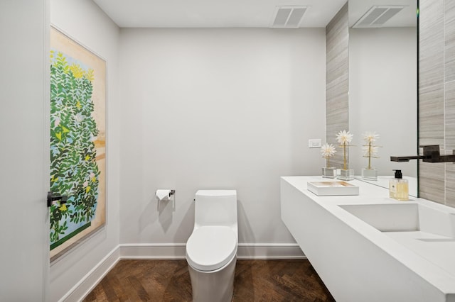 bathroom with double vanity, baseboards, toilet, and visible vents