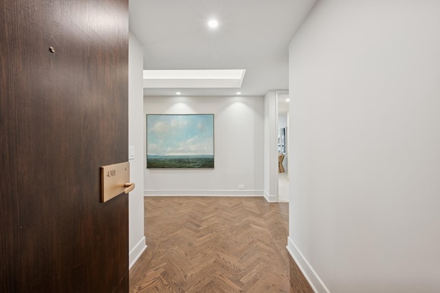 hallway featuring a skylight, baseboards, and recessed lighting