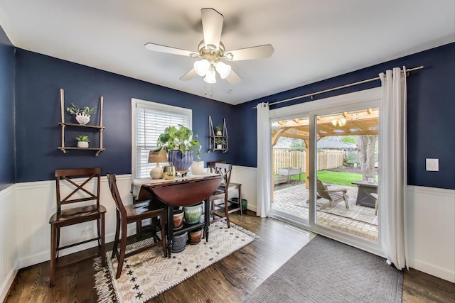 dining space with wainscoting, a ceiling fan, and wood finished floors