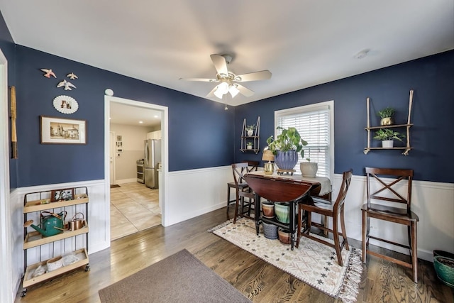 dining area featuring wainscoting, ceiling fan, and wood finished floors