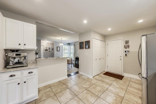kitchen with freestanding refrigerator, white cabinetry, light tile patterned flooring, baseboards, and recessed lighting