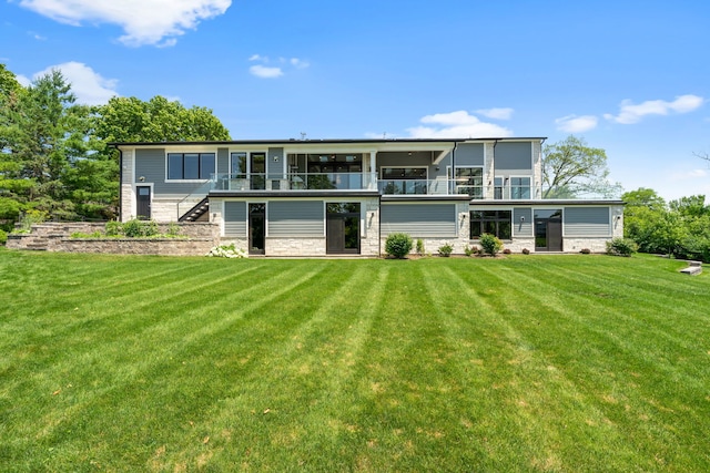 rear view of house featuring stairway, a yard, and stone siding
