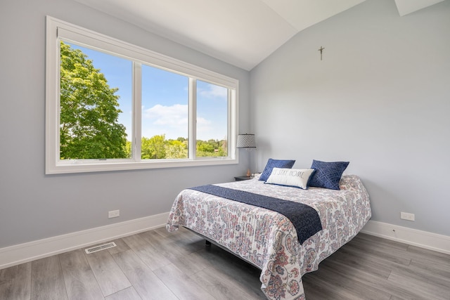 bedroom featuring baseboards, multiple windows, lofted ceiling, and visible vents