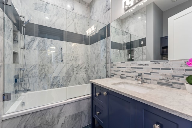 bathroom featuring combined bath / shower with glass door, tasteful backsplash, and vanity