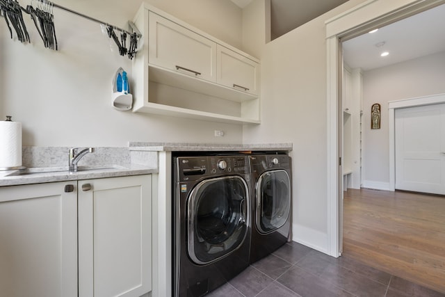 laundry room with washer and dryer, baseboards, dark tile patterned flooring, a sink, and cabinet space