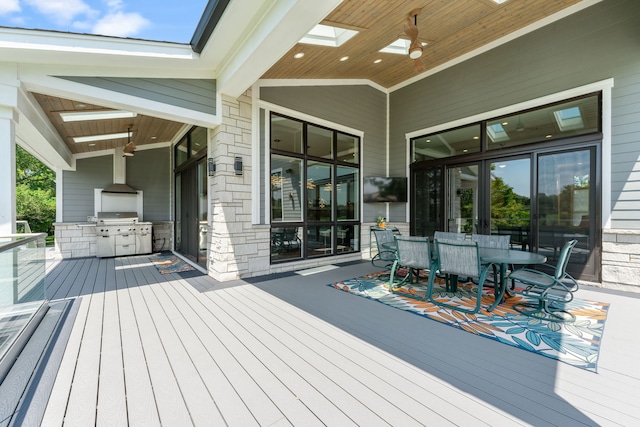 deck featuring grilling area, exterior kitchen, a ceiling fan, and outdoor dining area
