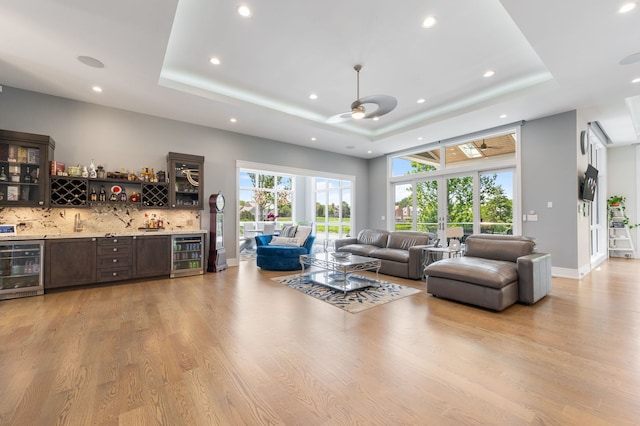 living area with indoor wet bar, a tray ceiling, and wine cooler