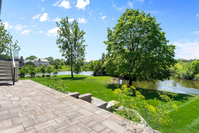 view of community featuring a lawn, a water view, stairs, and a patio