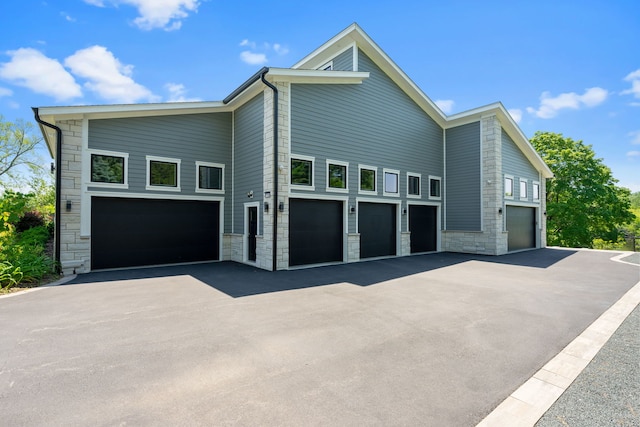 view of home's exterior featuring a garage, aphalt driveway, and stone siding