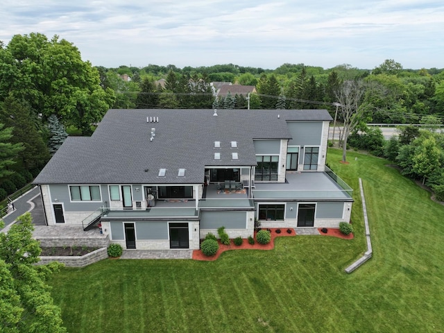 rear view of house with a lawn, a shingled roof, and a balcony
