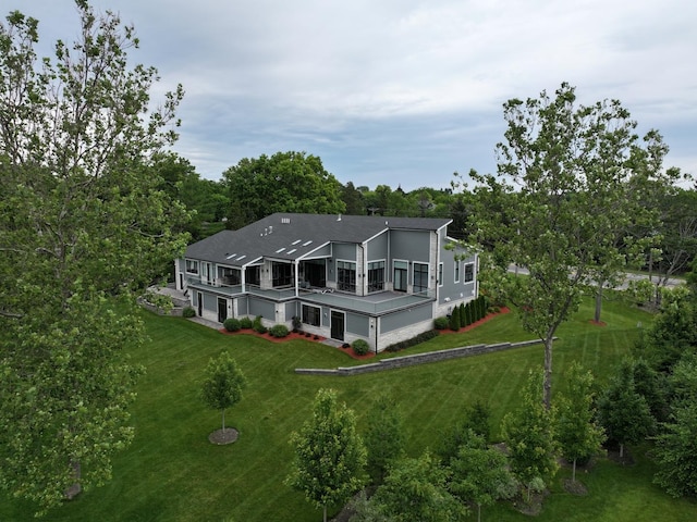 back of property featuring a yard, an attached garage, and a balcony