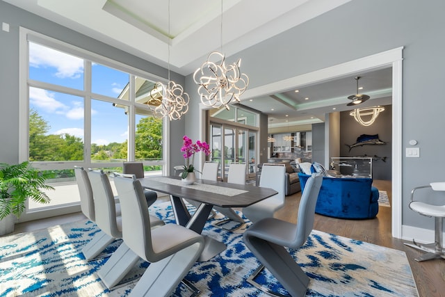 dining area with a notable chandelier, a raised ceiling, recessed lighting, baseboards, and wood finished floors