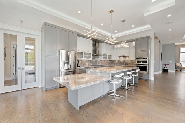 kitchen with decorative backsplash, a large island, appliances with stainless steel finishes, light wood-type flooring, and gray cabinetry