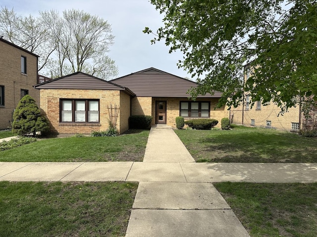 bungalow with brick siding and a front lawn