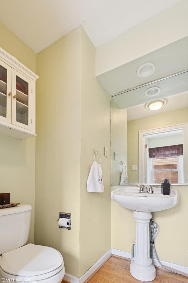 half bath featuring toilet, baseboards, and wood finished floors