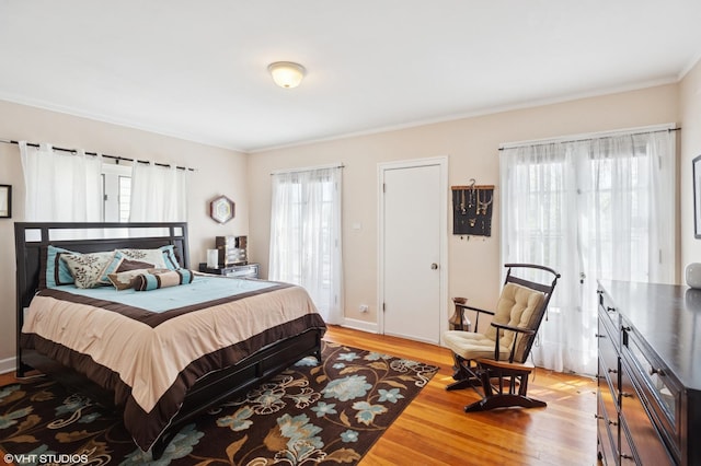 bedroom with light wood-style floors, baseboards, and crown molding