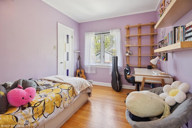 bedroom featuring baseboards, ornamental molding, and light wood finished floors