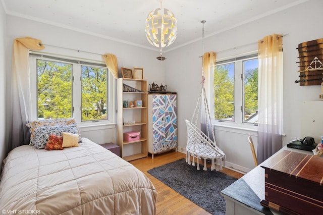 bedroom featuring baseboards, ornamental molding, and wood finished floors