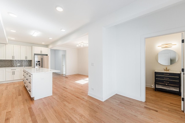 4134 W Roscoe St, Chicago, IL 60641 - kitchen with high end refrigerator, light wood finished floors, white cabinetry, backsplash, and a center island