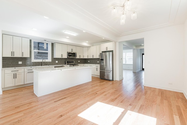 4134 W Roscoe St, Chicago, IL 60641 - kitchen featuring stainless steel appliances, backsplash, a kitchen island, light countertops, and light wood-style flooring