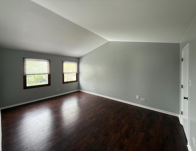 empty room featuring baseboards, dark wood finished floors, and lofted ceiling
