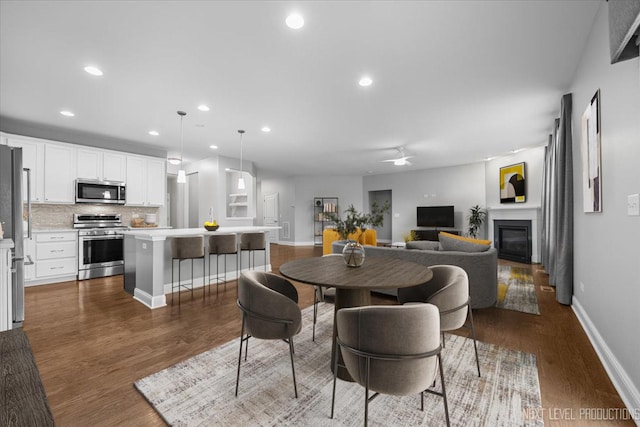 719 Foxborough Rd, South Elgin, IL 60177 - dining space with a glass covered fireplace, ceiling fan, dark wood-style flooring, recessed lighting, and baseboards