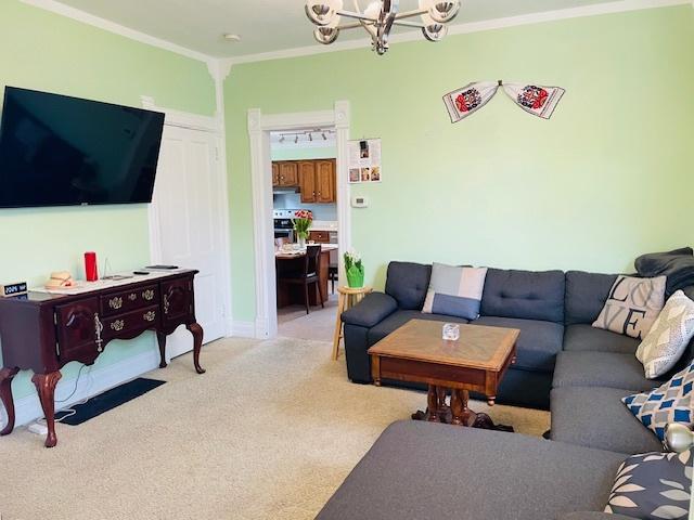 242 N Grove St, Carpentersville, IL 60110 - living room with ornamental molding, light colored carpet, and a notable chandelier
