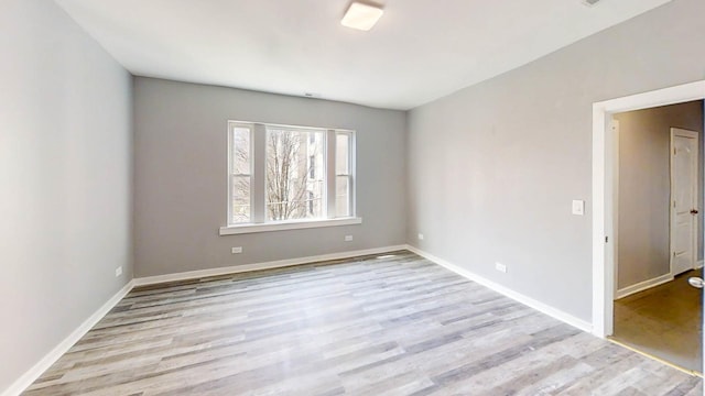spare room with baseboards and wood finished floors