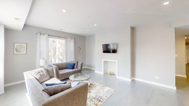 living room with wood finished floors, baseboards, and recessed lighting