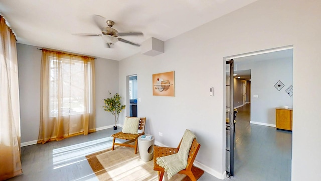 living area featuring wood finished floors, baseboards, and ceiling fan